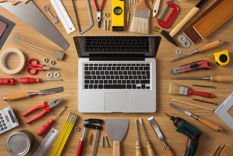 Laptop on a work table with DIY and construction tools all around top view hobby and crafts concept